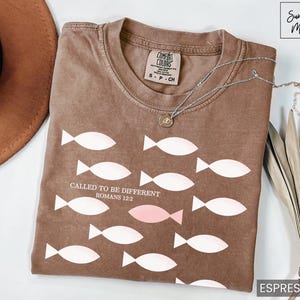 May include: A brown t-shirt with a white graphic of fish and the text "CALLED TO BE DIFFERENT ROMANS 12:2".