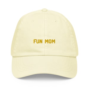 Puede incluir: Una gorra de b&eacute;isbol de color amarillo claro con el texto "FUN MOM" bordado en dorado en la parte delantera.