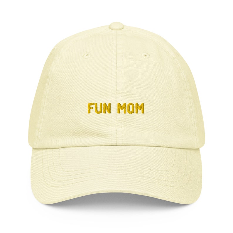 Puede incluir: Una gorra de b&eacute;isbol de color amarillo claro con el texto "FUN MOM" bordado en dorado en la parte delantera.