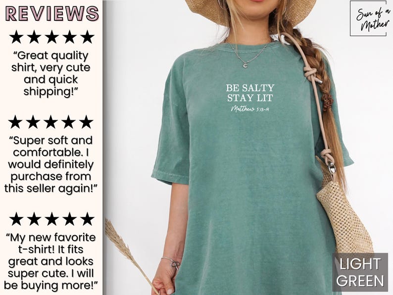 Puede incluir: Una camiseta verde claro con el texto "BE SALTY STAY LIT Matthew 5:13-14" impreso en la parte delantera. La camiseta la lleva puesta una persona con un sombrero de paja y un bolso de color marr&oacute;n claro.