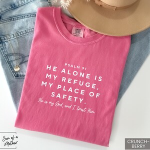 May include: Pink t-shirt with the text "PSALM 91 HE ALONE IS MY REFUGE, MY PLACE OF SAFETY. He is my God, and I trust Him."