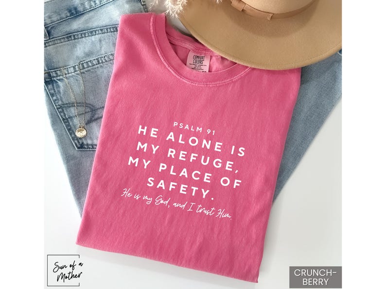 May include: Pink t-shirt with the text "PSALM 91 HE ALONE IS MY REFUGE, MY PLACE OF SAFETY. He is my God, and I trust Him."