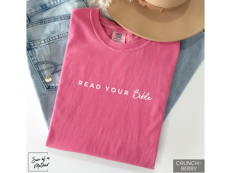 May include: A pink t-shirt with the text "Read Your Bible" in white lettering.