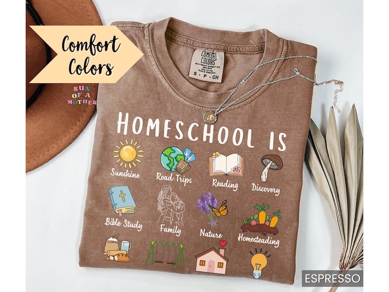 K&ouml;nnte beinhalten: Espressofarbenes T-Shirt mit der Aufschrift "Homeschool Is" und Illustrationen von Sonnenschein, Roadtrips, Lesen und mehr. Das Shirt tr&auml;gt auch den Text "Comfort Colors" und "Sun of a Mother."