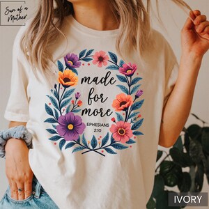 K&ouml;nnte beinhalten: Ein wei&szlig;es T-Shirt mit einem floralen Design und dem Text "made for more Ephesians 2:10".