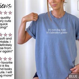 May include: Blue jean colored t-shirt with the text "it's not dog hair it's labrador glitter" in white. The shirt has rolled-up sleeves and is part of a clothing collection. The image also includes customer reviews.