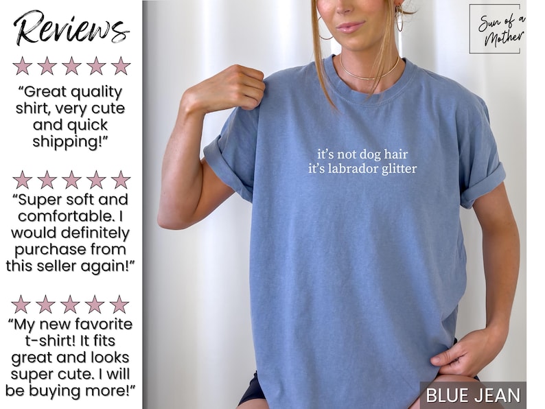 May include: Blue jean colored t-shirt with the text "it's not dog hair it's labrador glitter" in white. The shirt has rolled-up sleeves and is part of a clothing collection. The image also includes customer reviews.