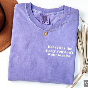 May include: A purple t-shirt with the text "Heaven is the party you don't want to miss" printed in white.