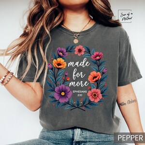 K&ouml;nnte beinhalten: Ein graues T-Shirt mit einem Blumendesign und dem Text "made for more Ephesians 2:10".