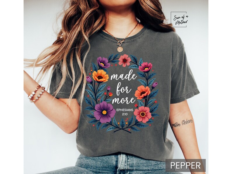 K&ouml;nnte beinhalten: Ein graues T-Shirt mit einem Blumendesign und dem Text "made for more Ephesians 2:10".