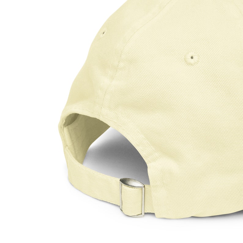 Puede incluir: Una gorra de b&eacute;isbol de color amarillo claro con una correa de tela y un cierre de hebilla de metal.