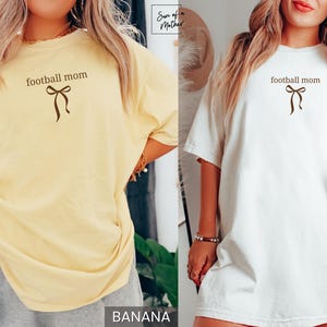 May include: Two t-shirts, one banana yellow and one white, each with the text "football mom" above a brown bow graphic. The shirts are short-sleeved and appear to be made of a soft material.