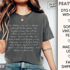 May include: A gray t-shirt with a white print of the Lord's Prayer. The shirt is made with a soft, vintage feel and is printed with ink. The shirt is made in the USA and ships quickly.