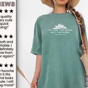 Peut inclure: Un t-shirt vert clair avec le texte "FOLLOW THE WORD. NOT THE HERD. ISAIAH 8:11-12" en blanc. Le t-shirt pr&eacute;sente un graphique d'un groupe de moutons.