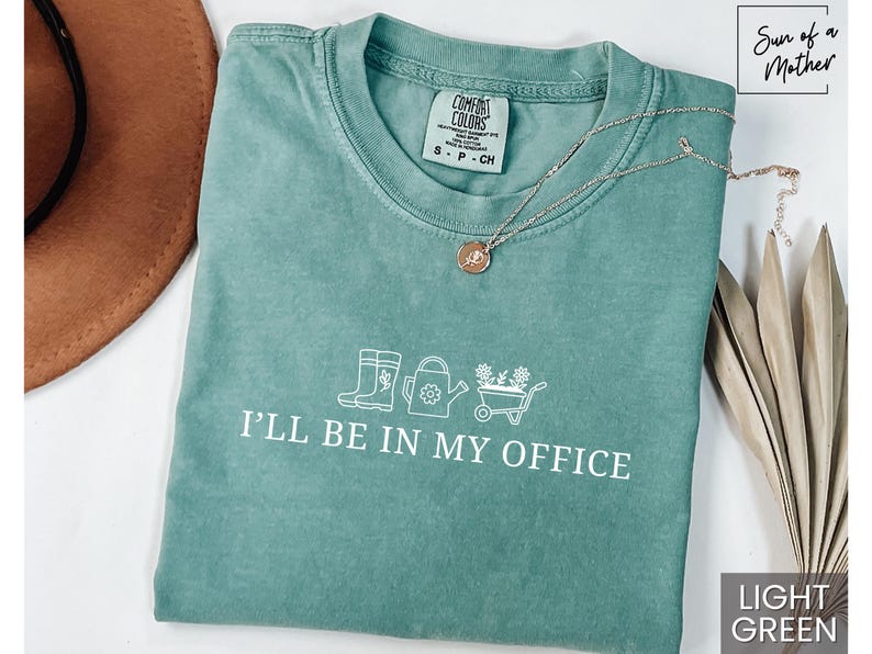 May include: Light green t-shirt with a white graphic of gardening tools and the text "I'll be in my office".