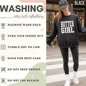 May include: Black sweatshirt with the text "BUTTER GIRL" in white. The sweatshirt has a care label with instructions for washing, drying, and ironing. The instructions include machine wash cold, turn item inside out, tumble dry low, hang for best care, do not iron design, and do not use bleach.