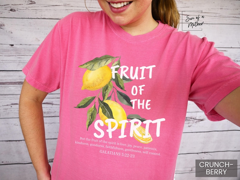 Op de afbeelding: Roze T-shirt met een witte afbeelding van citroenen en de tekst "Fruit of the Spirit" met een Bijbelvers uit Galaten 5:22-23.
