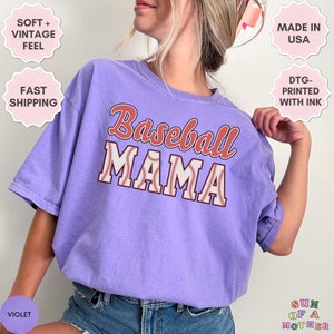 May include: Purple t-shirt with the text "Baseball Mama" in red and white lettering with a baseball graphic. The shirt is made of a soft, vintage feel fabric.
