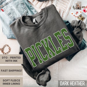 Op de afbeelding: Donkergrijs sweatshirt met een groene "PICKLES" print op de voorkant.