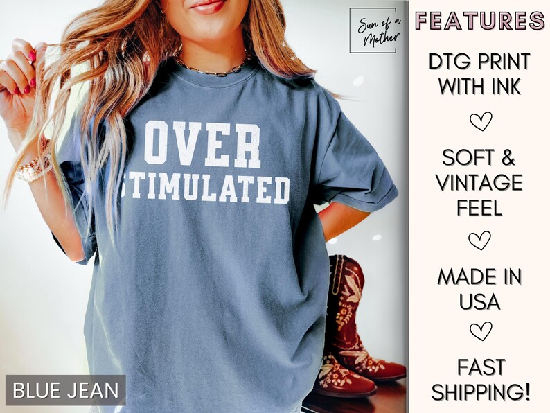 May include: A blue jean t-shirt with the text "OVER STIMULATED" printed in white. The shirt is a relaxed fit and has a soft, vintage feel.