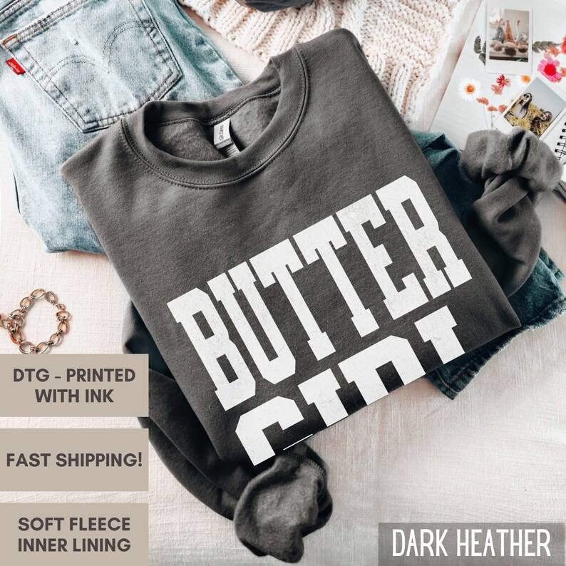 May include: Dark heather grey sweatshirt with the text "BUTTER CIN" printed in white.