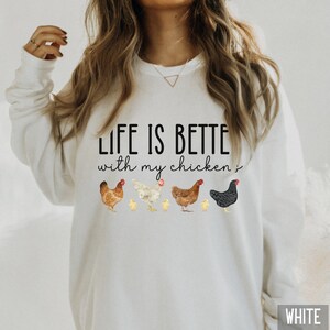 May include: White sweatshirt with the text "Life is better with my chickens" and a line of chickens and chicks printed on the front.