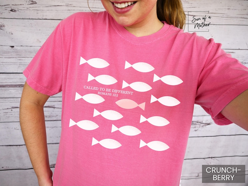 May include: Pink t-shirt with a white graphic of fish and the text "Called to be different Romans 12:2".