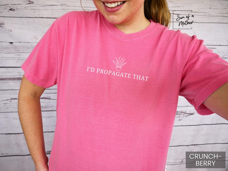 May include: Pink t-shirt with the text "I'd Propagate That" and a small illustration of a potted plant.