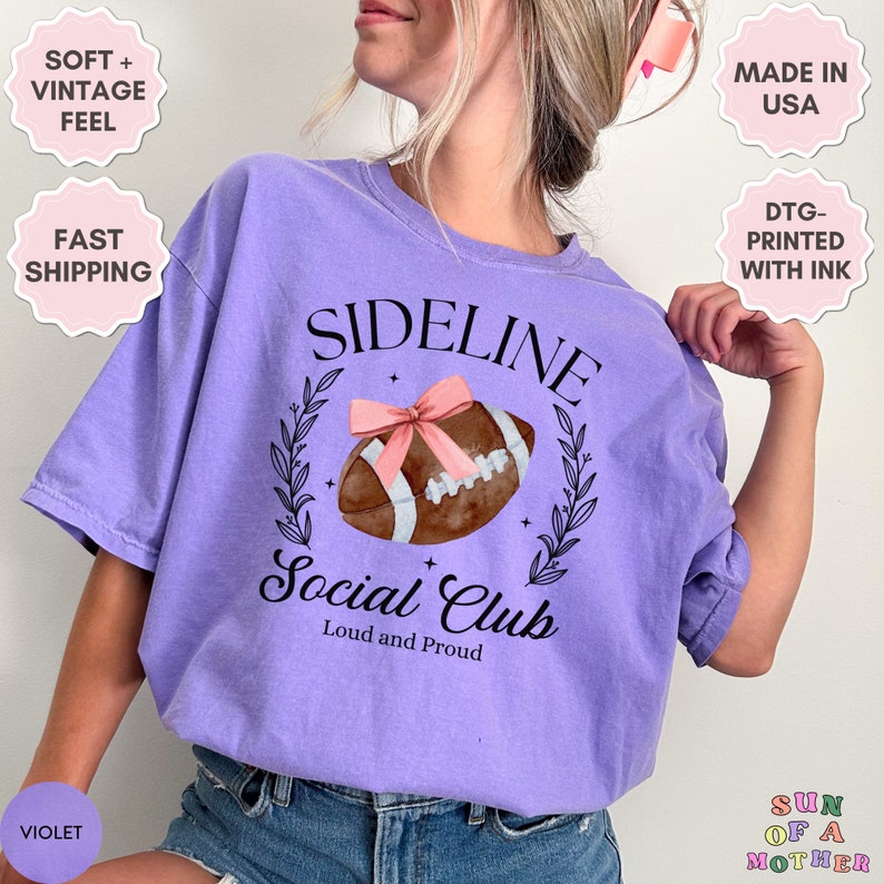 以下が含まれることがあります： 紫色のTシャツに、フットボールのグラフィックと「Sideline Social Club Loud and Proud」の文字がプリントされています。