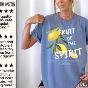 Op de afbeelding: Een jeansblauw T-shirt met een aquarel-illustratie van citroenen en bladeren. De tekst "Fruit of the Spirit" is in wit op het shirt gedrukt, samen met een Bijbelvers uit Galaten 5:22-23.