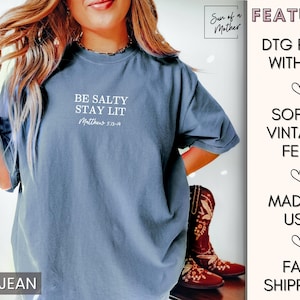 Puede incluir: Una camiseta azul vaquero con el texto "Be Salty Stay Lit Matthew 5:13-14" impreso en la parte delantera. La camiseta est&aacute; hecha con una sensaci&oacute;n suave y vintage y est&aacute; impresa con tinta.