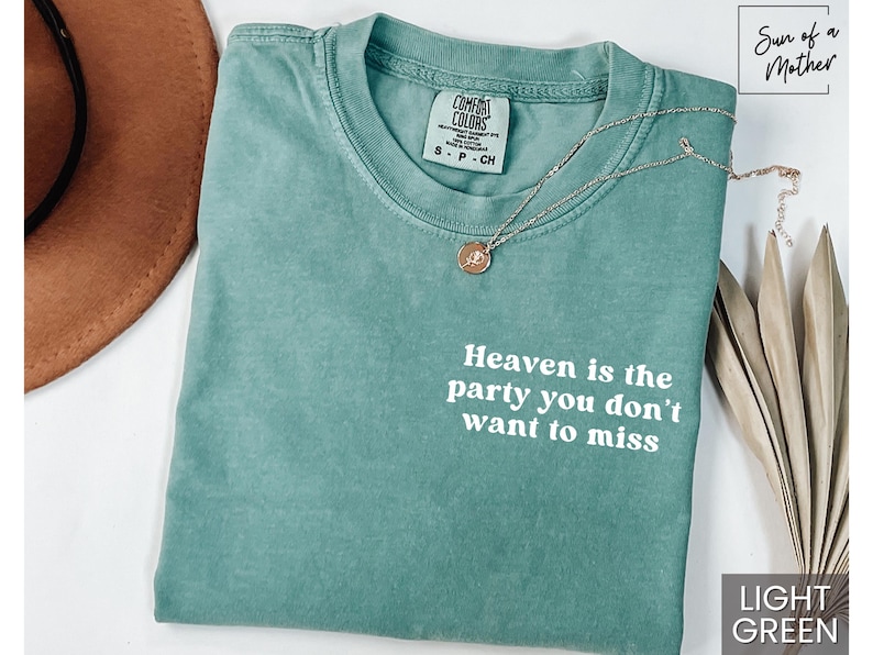 May include: Light green t-shirt with the text "Heaven is the party you don't want to miss" printed in white. The shirt is made of a soft, comfortable material and has a distressed look.