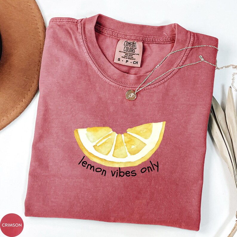 K&ouml;nnte beinhalten: Ein maroonfarbenes T-Shirt mit einem gelben Zitronenscheiben-Motiv und dem Text "lemon vibes only".