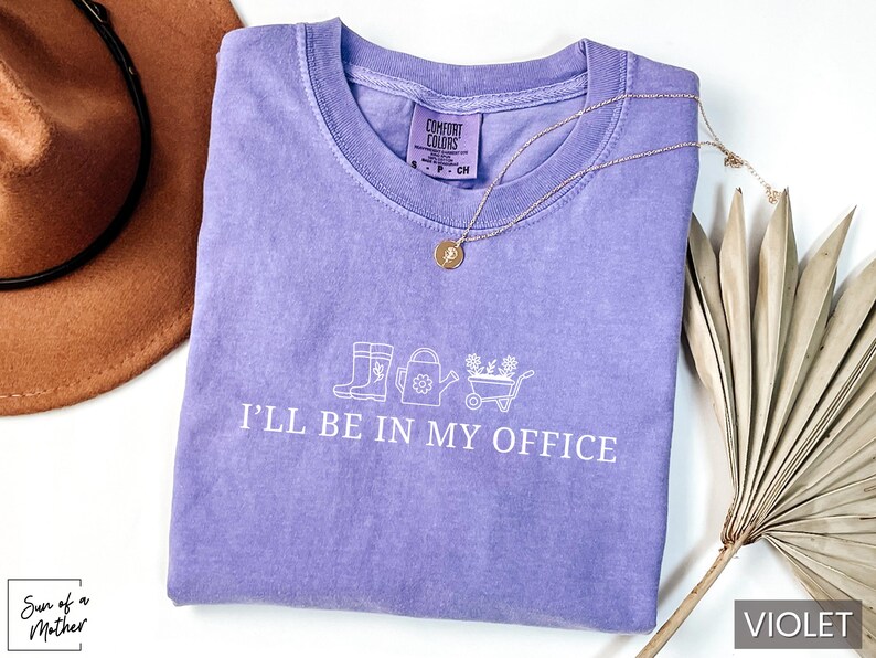 May include: A purple t-shirt with the text "I'll be in my office" and a graphic of gardening tools.
