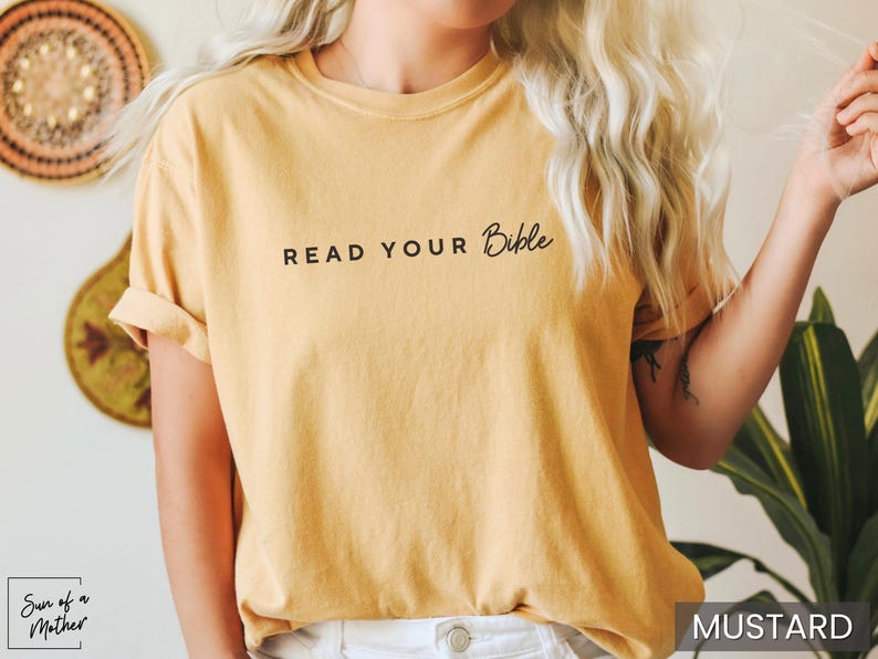 May include: A mustard yellow t-shirt with the text "READ YOUR Bible" printed in black.