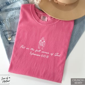 Puede incluir: Camiseta rosa con texto blanco que dice "Ponte la armadura completa de Dios Efesios 6:10-18".