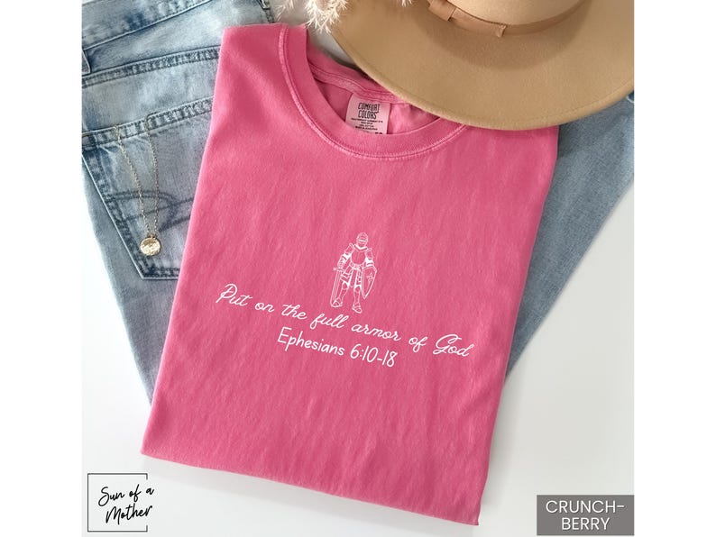 Puede incluir: Camiseta rosa con texto blanco que dice "Ponte la armadura completa de Dios Efesios 6:10-18".