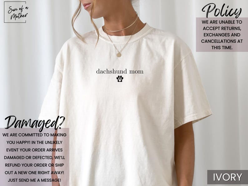 以下が含まれることがあります： 「dachshund mom」の文字と足跡のグラフィックが入ったアイボリー色のTシャツ。ショップのポリシーと破損したアイテムに関するテキストも含まれています。