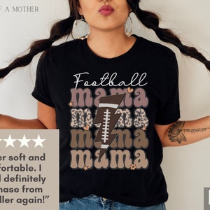 Puede incluir: Camiseta negra con el texto "Football mama" en letras marrones y rosas con un gr&aacute;fico de bal&oacute;n de f&uacute;tbol y rayo. La camiseta tiene un dise&ntilde;o de estampado de leopardo.