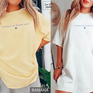 Puede incluir: Camisetas amarillas y blancas con la frase "reading is my favorite sport" en azul y un coraz&oacute;n azul. Las camisetas son informales y c&oacute;modas, adecuadas para el uso diario.