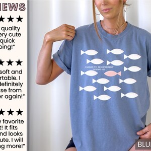 May include: A blue jean t-shirt with a white fish design and the text "Called to be different Romans 12:2" in white. One fish is pink.