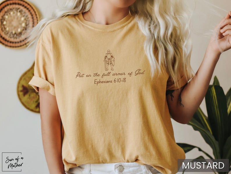 Puede incluir: Camiseta amarilla mostaza con un dibujo lineal de una persona con armadura y el texto "Ponte la armadura completa de Dios Efesios 6:10-18".
