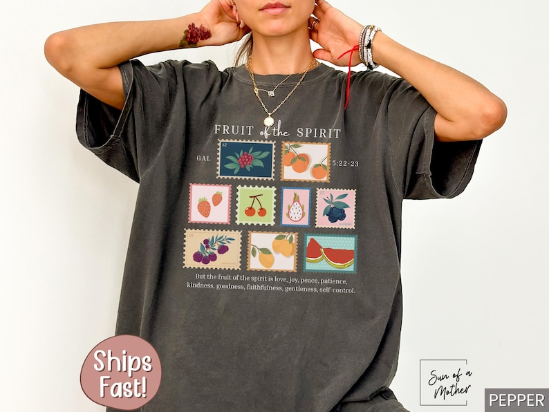 May include: A dark gray t-shirt with a graphic print of fruit and the text "FRUIT of the SPIRIT GAL 5:22-23" and "But the fruit of the spirit is love, joy, peace, patience, kindness, goodness, faithfulness, gentleness, self control".