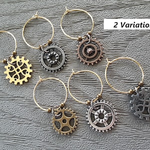 May include: Six gold-toned wine glass charms with different gear designs. Two variations of gear designs are shown: one with a cross-shaped center and one with a circular center. The charms are labeled "2 Variations".