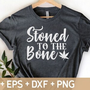 May include: A dark gray t-shirt with the text "Stoned to the Bone" in white lettering and a white marijuana leaf graphic.