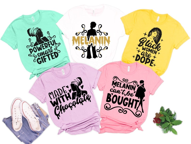 May include: Five different t-shirts with black text and graphics on various colored shirts. The shirts feature phrases like "Powerful, smart, gifted", "Melanin", "Black women are dope", "Made with chocolate", and "Melanin can't be bought".