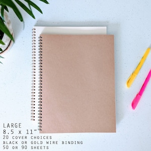May include: A large spiral-bound notebook with a tan cover and a white cover underneath. The notebook is 8.5 x 11 inches. Text on the image reads: "LARGE 8.5 x 11" 20 COVER CHOICES BLACK OR GOLD WIRE BINDING 50 OR 90 SHEETS."