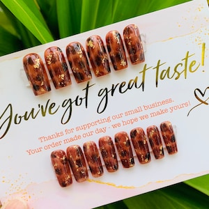 May include: A set of press-on nails with a brown leopard print design and gold foil accents. The nails are displayed on a card with the text "You've got great taste!" and a thank you message.