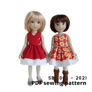 May include: Two dolls wearing dresses. The doll on the left is wearing a red dress with a white trim. The doll on the right is wearing a white dress with orange flowers and a white trim. The text "SBL 003 - 2021 PDF sewing pattern" is at the bottom of the image.