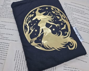 May include: Black pouch featuring a gold witch silhouette against a full moon, stars, and bats. The design is set within a tree-like frame. The pouch is made of a dark fabric and is likely used for storage or carrying small items. The design is reminiscent of Halloween.